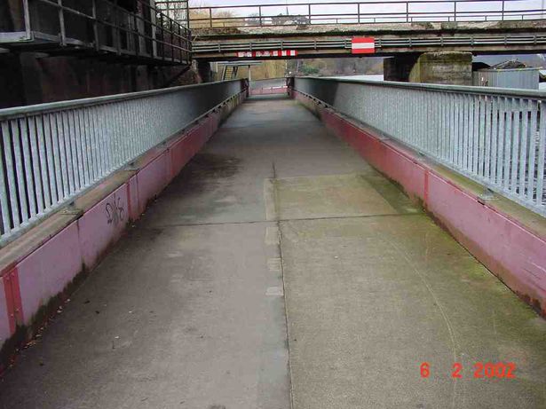 auf der Brücke in Richtung Norden fotografiert, links oben im Bild ein an das östliche Wiederlager der Obergrabenbrücke angebrachtes Podest, oben im Bild überquert die Obergrabenbrücke der Eisenbahn (BAS 13006) die Radwegbrücke